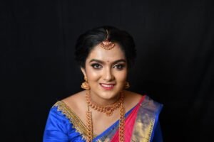 Portrait of a South Asian woman wearing traditional attire, adorned with jewelry, smiling.